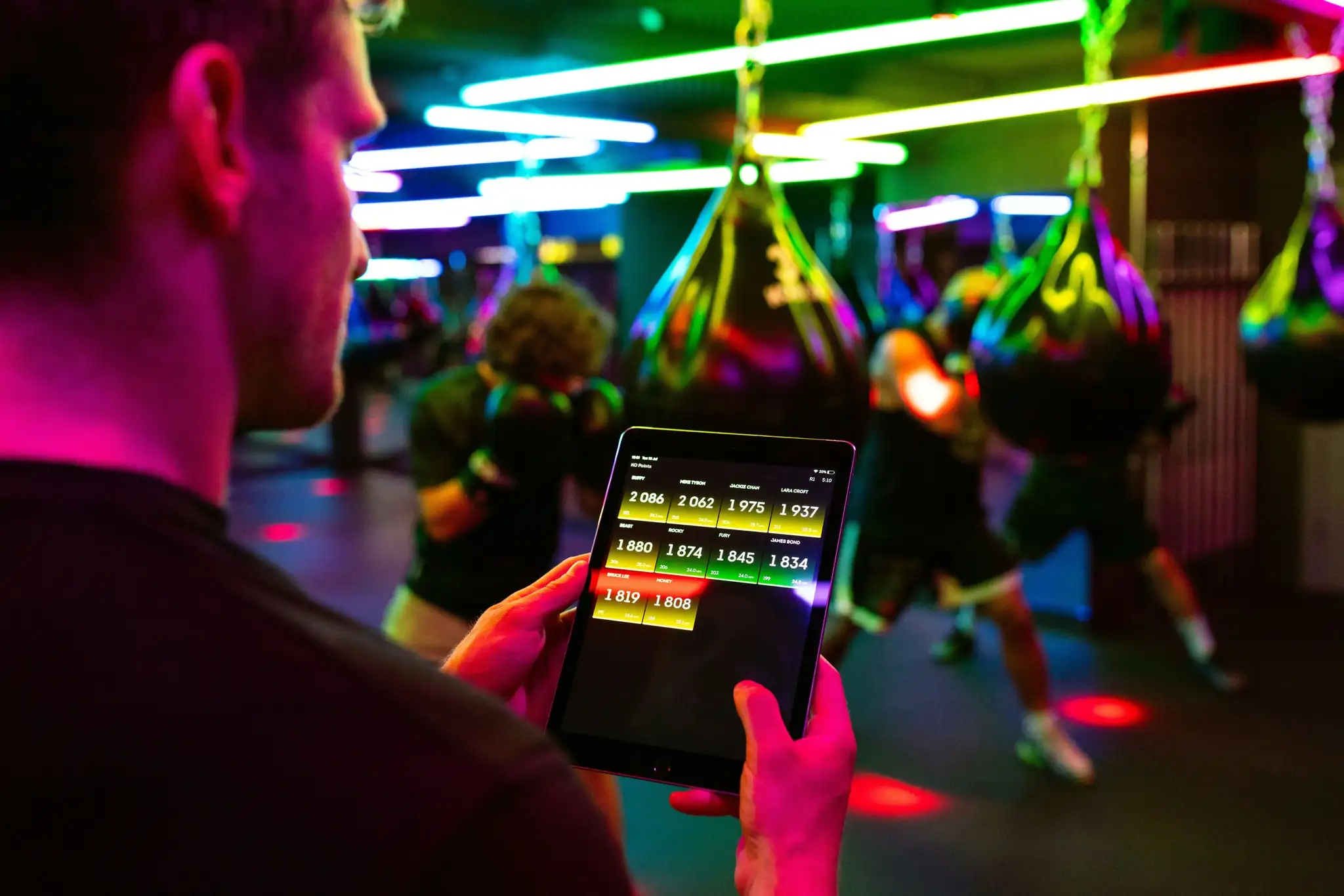 Person tracking performance metrics on a tablet in a neon-lit gym